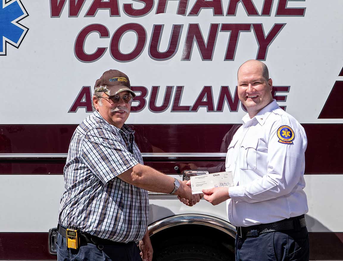 Man handing a check to ambulance employee